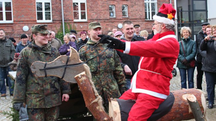 zeigt den Weihnachtsmann auf einem Holzpferd und umstehende Personen