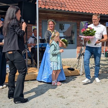 zeigt Gruppen von 4 Personen, wobei ein Mann einen Blumenstrauß übergibt