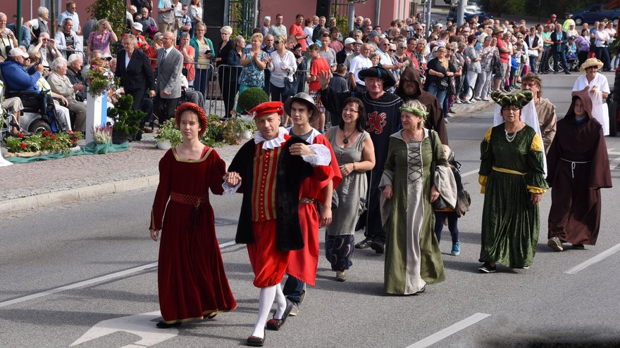 zeigt Abschnitt des Festumzugs mit historisch gekleideten Menschen und Zuschauergruppen am Straßenrand
