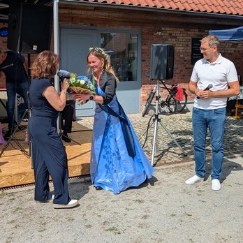 zeigt mehrere Personen und die Blaubeerkönigin, die sich begrüßen