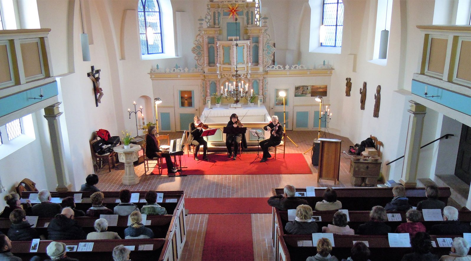 zeigt Innenansicht der Liepgartener Kirche mit musizierendem Ensemble und Zuhörern