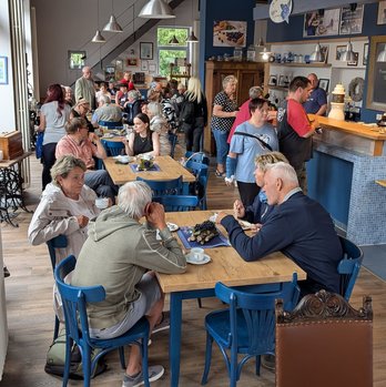 zeigt Blick in die Blaubeerscheune mit essenden Personen