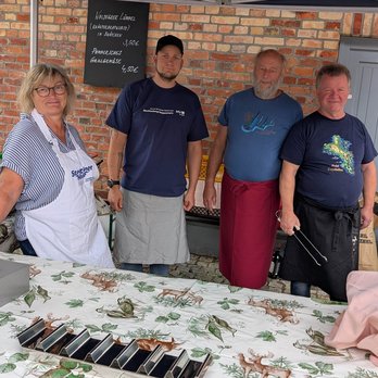 zeigt 4 Personen hinter einem Grillstand